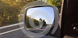 Car rear view mirror with the image of a biker approaching to overtake