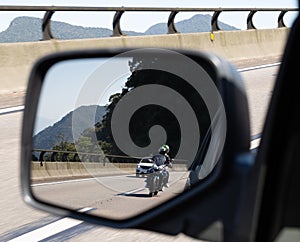Car rear view mirror with the image of a biker approaching to overtake photo