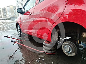 Car with rear wheel removed, lifted by hydraulic jack, car repair on the roadside