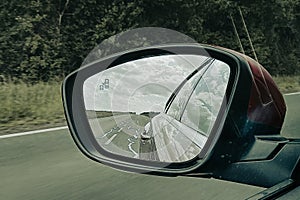 Car rearview mirror modern vehicle in road back view and cloudy sky