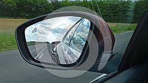 Car rearview mirror modern vehicle in road view and clouds