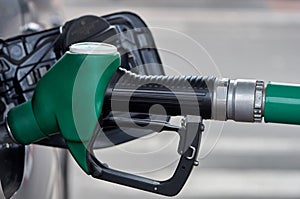 The car is refueled with gasoline at a gas station, in the tank is a green gun for fuel