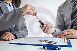 Car rent agent manager holding key of new car giving to businessman client after signing good deal agreement contract, renting