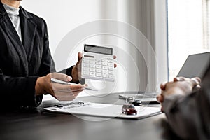 A car rental company employee holds a white calculator to show the tenant the rental price.