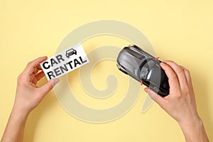 Car rental concept. Human hands holding toy car model and text sign