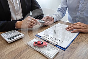 Car rental and Insurance concept, Young salesman giving car`s key to customer after sign agreement contract with approved for ren