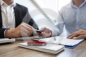 Car rental and Insurance concept, Young salesman giving car`s key to customer after sign agreement contract with approved for ren