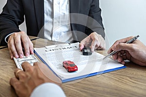 Car rental and Insurance concept, Young salesman receiving money and giving car`s key to customer after sign agreement contract