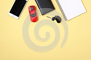 Car rental or sharing concept. Smartphone, driver license, toy car and automobile key on yellow background. Hire a car, renting