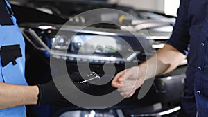 Car repair. Man owner of the auto gives the keys to the car repairman. Vehicle breaks down. Close up shot of hands of