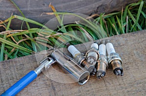 Car repair. Replacing spark plugs. Old spent candles covered with soot on the background of a wooden board