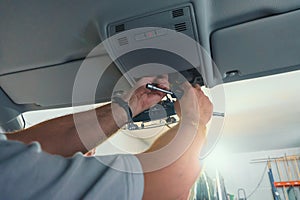Car repair. Serviceman repairs electrical wiring inside car. Replacing windshield with disconnecting sensors