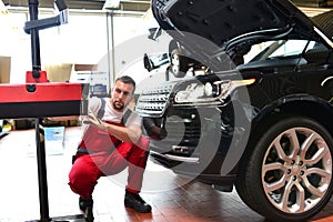 Car repair shop - worker checks and adjusts the headlights of a