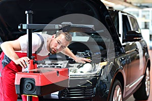 Car repair shop - worker checks and adjusts the headlights of a