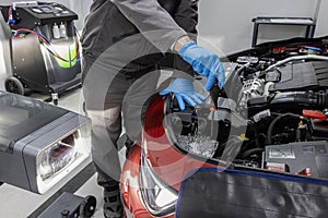 car repair shop worker checks and adjusts the headlights of a car's lighting