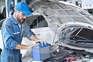Car repairs. Auto services and Small business concepts. A car mechanic is replacing the battery in an auto repair center