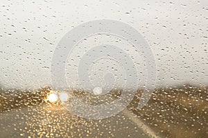 The car rides along the autumn road with rain drops on the windshield car window