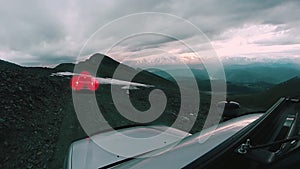 Car rides from the mountain along a dangerous road on a cloudy day. Auto travel: POV - Point of view SUV rides a valley