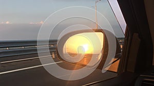 Car rides on the road, a view of the side rearview mirror, reflection in the mirror. View of the bay from the car. Close