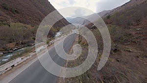 Car riding on empty highway asphalt road mountain river creek cliff desert stone slope aerial view