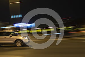 Car on the road driving fast through night city. Blurred city lights. Motion blur background