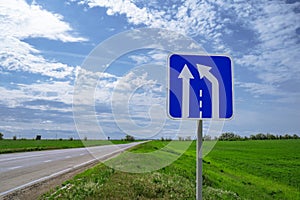 Car road sign `The end of the additional lane on the rise or runaway strip` against a blue sky