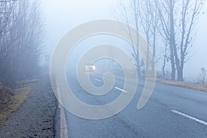 Car on the road in thick fog in bad weather