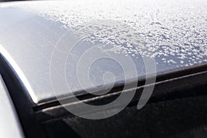 Car roof covered with frost. at the edge its free of hoarfrost. Amazing winter pattern on metal