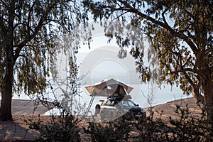 Car rooftop tent for camping on the roof rack of an off-road car by the lakeside