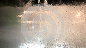 Car running through automatic carwash. Windscreen view from inside.