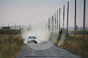 Car running on a bad road, leaving smoke and dust behind