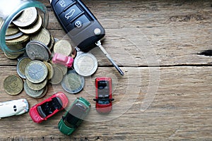 Car running cost as maintenance or insurance with toy cars, money savings and car key on wooden background