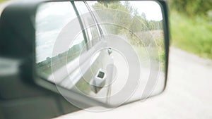 The car rushes along a country road. View through the rear view mirror.