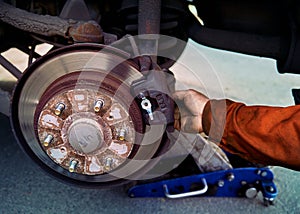 Car rusty brake rotor in automobile workshop front photo with jack and mechanic hand