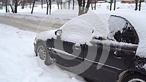 A car`s front part buried in snow after a blizzard.