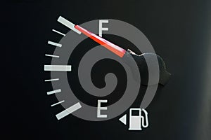 The car`s fuel gauge shows a full, close-up, rough black panel.