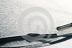 Car`s windscreen wiper covered in snow