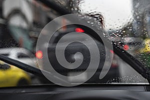 Car`s windshield wipers slightly working while few rain softly drops on.