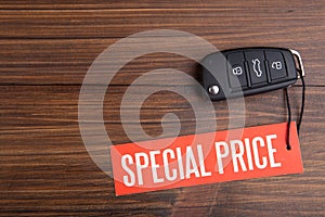 Car sale concept. Special price! Vehicle security key with tag on the wooden background