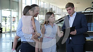 Car sales, attractive manager sells automobile to visitors, happy family