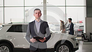 car sales center, portrait of a male sales manager background of happy owners of a new automobile in an auto showroom