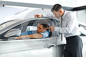 Car Sales Consultant Showing a New Car to a Potential Buyer