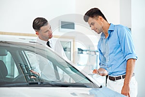 Car Sales Consultant Showing a New Car to a Potential Buyer in S