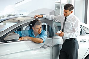 Car Sales Consultant Showing a New Car to a Potential Buyer in S