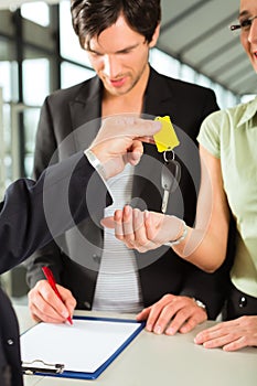 Car sales - dealer handing woman auto key