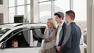 car sales manager consulting a young family with a male child about choosing automobile in an auto sale center