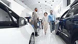 Car Sales Manager Showing Auto To Buyers In Dealership Store