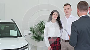 A car sales manager shows a new electric car in a car showroom. Car sales concept