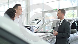 A car sales manager shows a new electric car in a car showroom. Car sales concept