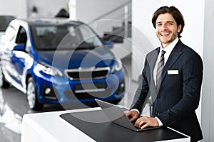 Car Sales Manager Standing In Luxury Dealership Office